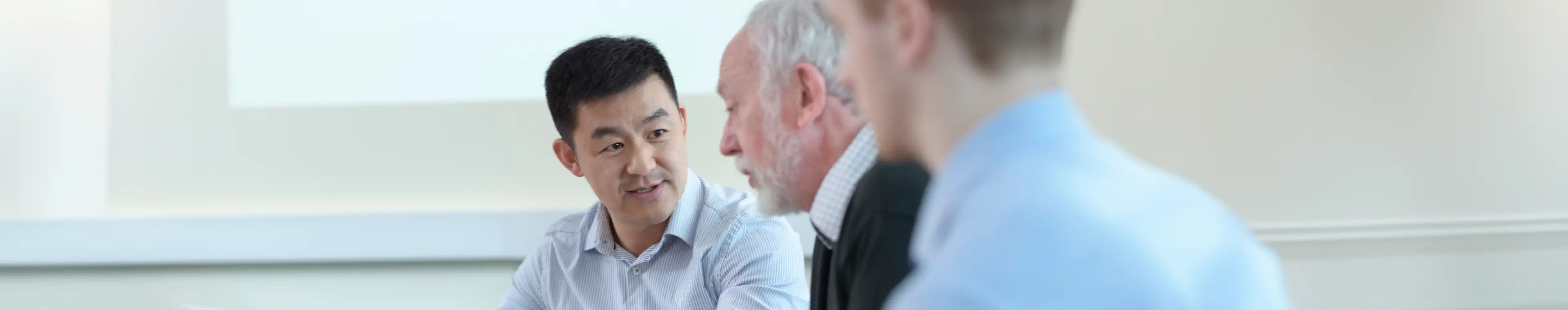 Younger and older colleagues discuss a project in a meeting room