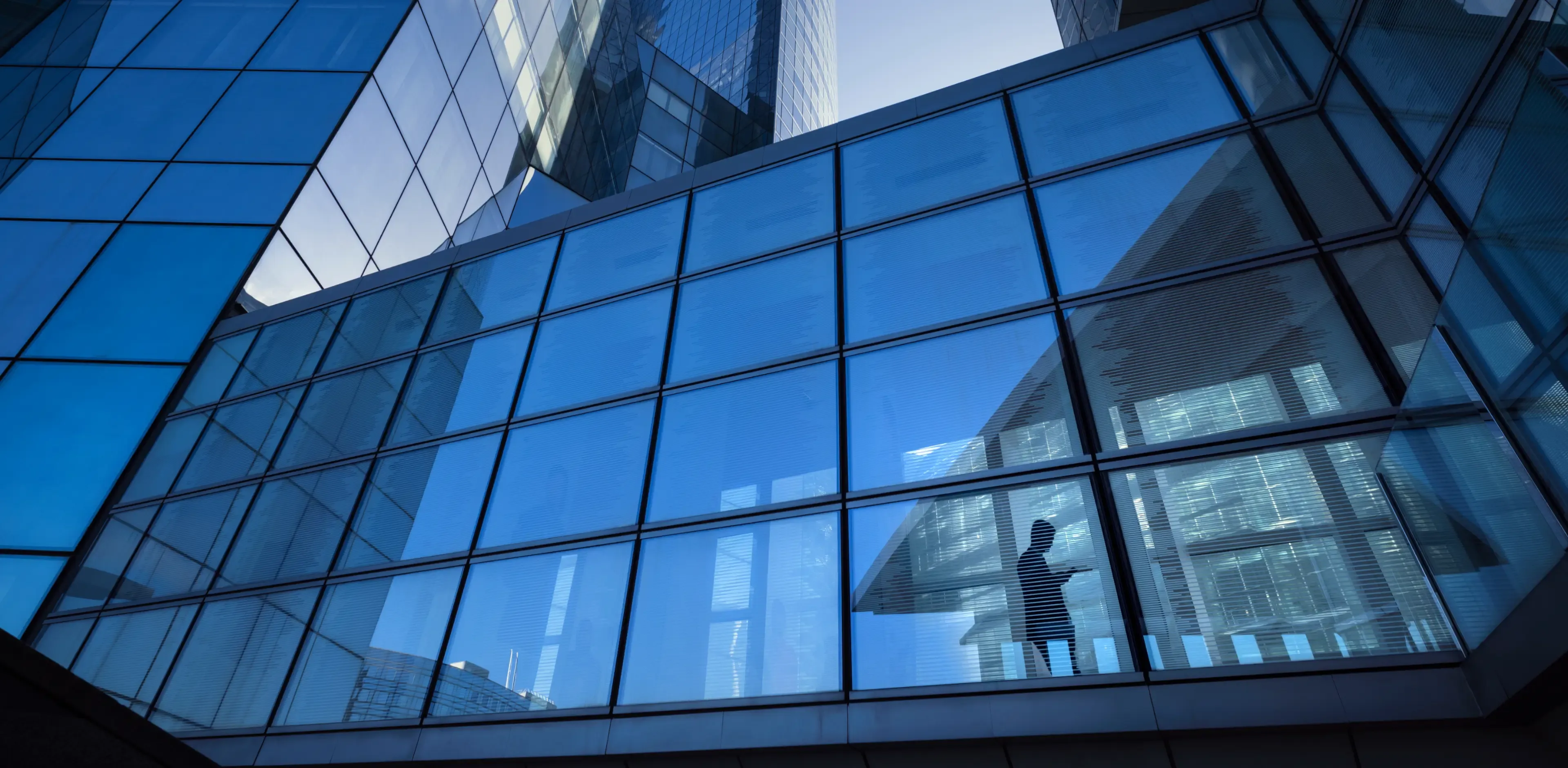 Modern office buildings with the silhouette of a businessperson crossing an elevated overpass